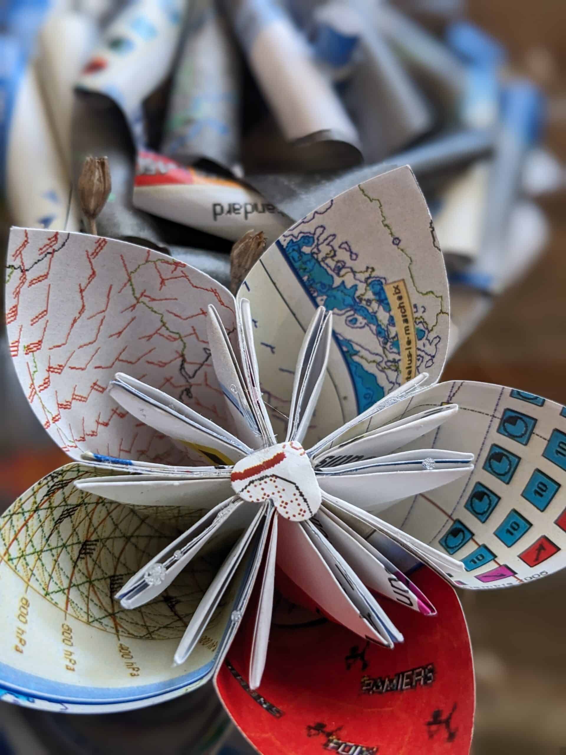 Cette photo représente une fleur de papier réalisée à partir de cartes météorologiques