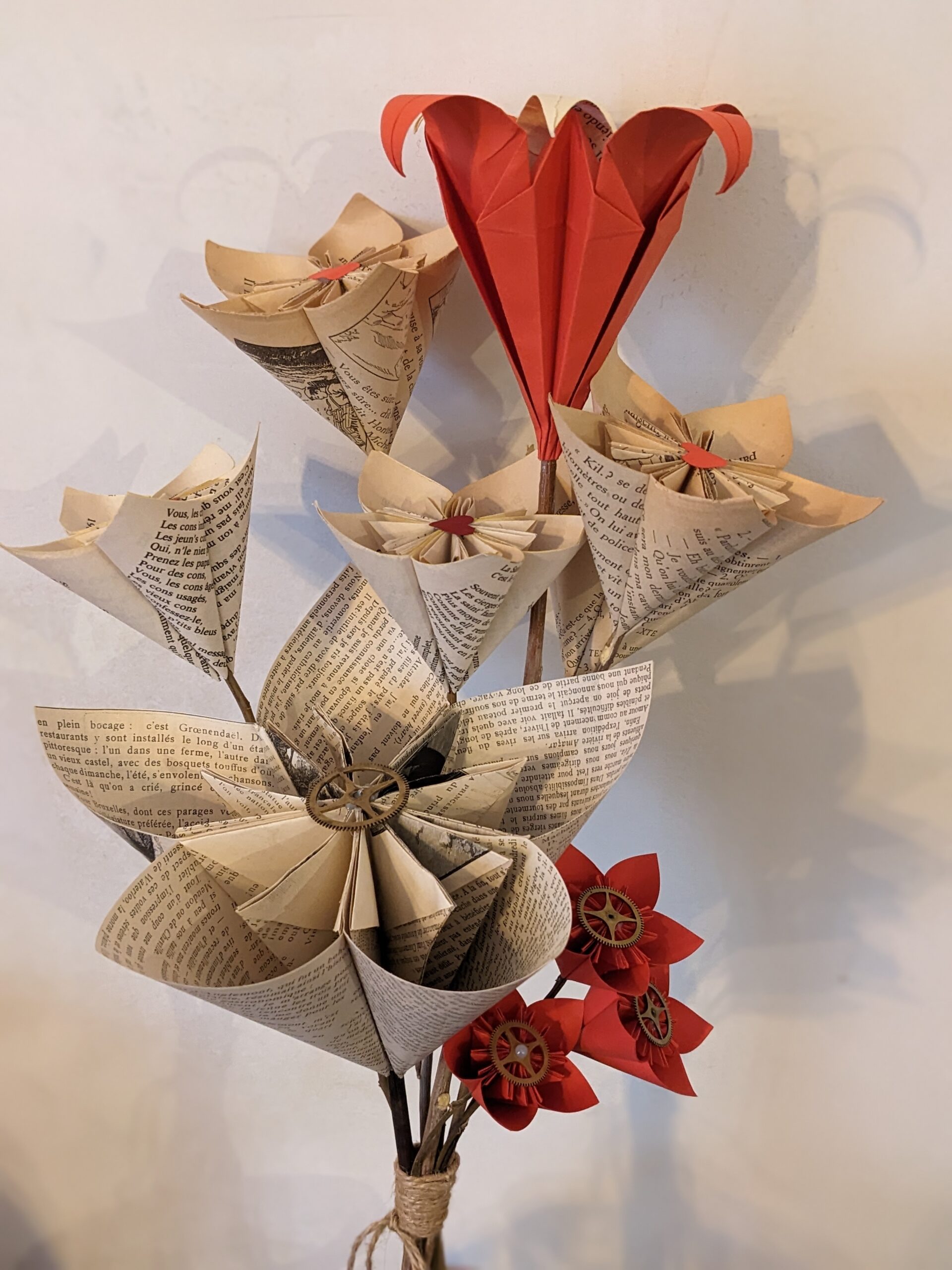Cette photo représente un gros bouquet de fleurs de papier réalisé à partir de vieilles pages de romans et de papier rouge.