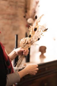 Cette photo représente Cécile Le Blanc en train de créer un bouquet de fleurs de papier et de fleurs séchées
