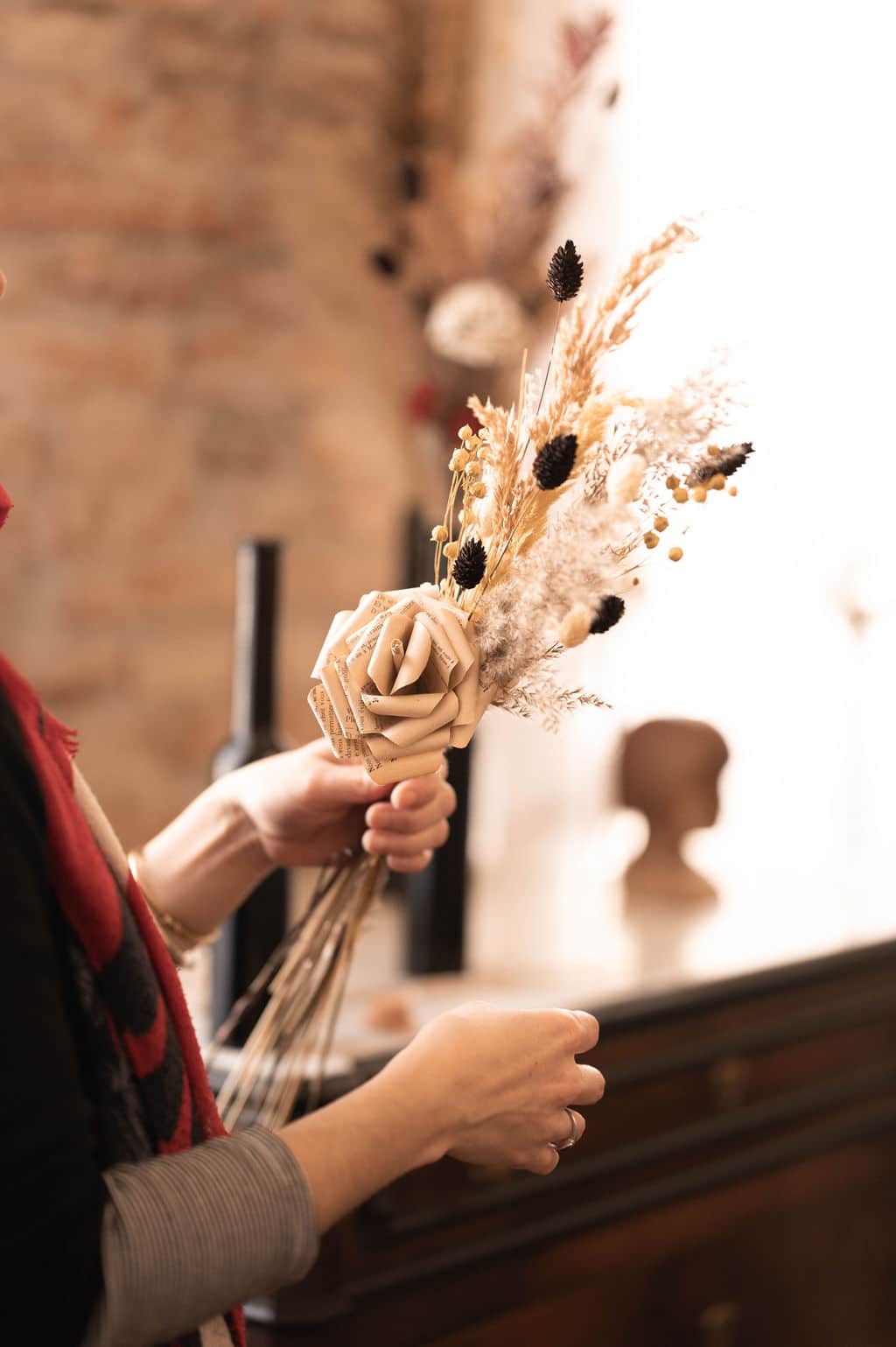 Cette photo représente Cécile Le Blanc en train de créer un bouquet de fleurs de papier et de fleurs séchées