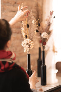 Cette photo représente Cécile Le Blanc en train de créer un bouquet de fleurs de papier et de fleurs séchées
