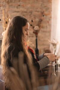 Portrait de Cécile Le Blanc de profil en train de créer un bouquet de fleurs de papier et de fleurs séchées