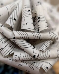 Cette photo représente un gros plan d'une rose réalisée à partir de partitions musicales