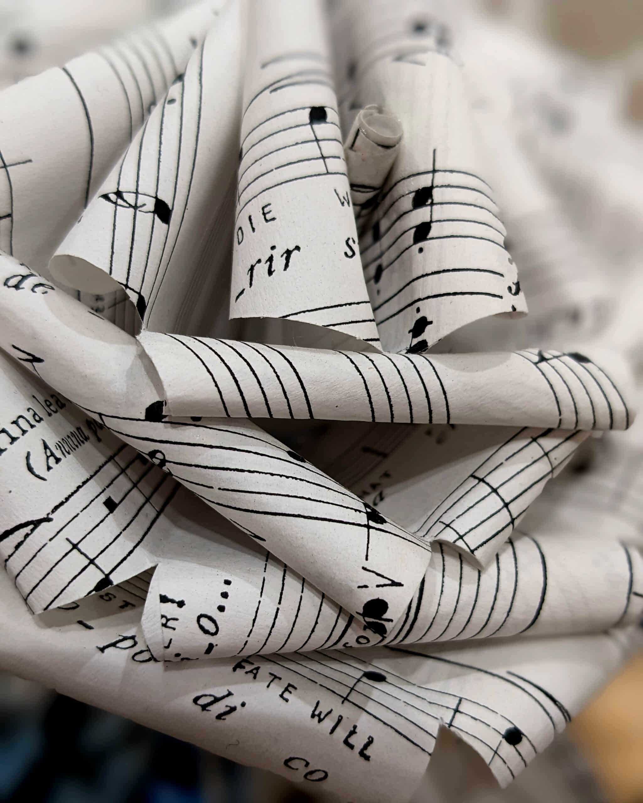 Cette photo représente un gros plan d'une rose réalisée à partir de partitions musicales
