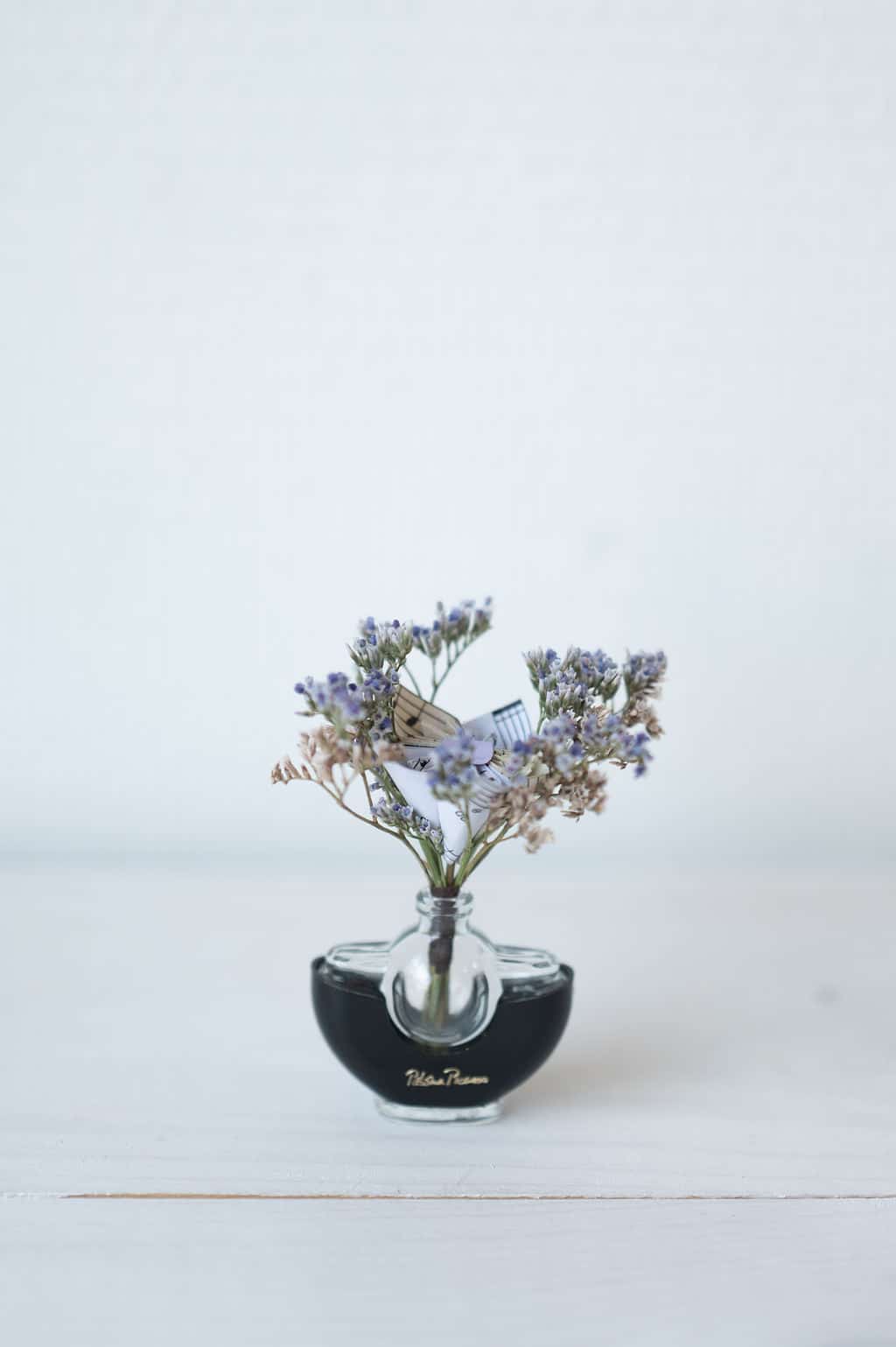 Cette photo représente une composition florale associant fleurs de papier et fleurs séchées dans les teintes violettes