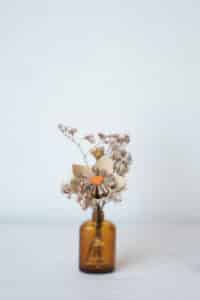 Cette photo représente une composition florale associant fleurs de papier et fleurs séchées dans les tons marrons et orange