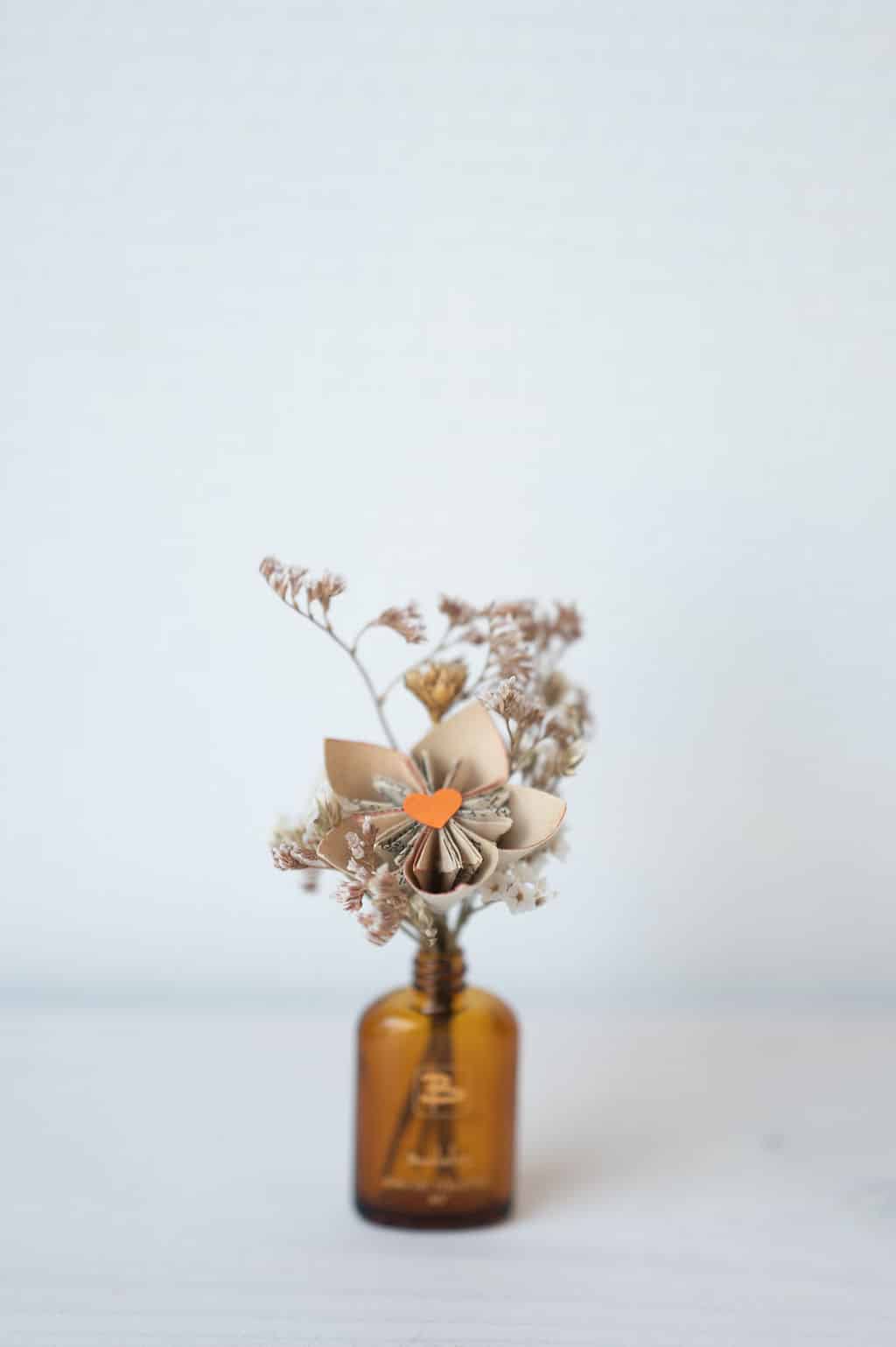 Cette photo représente une composition florale associant fleurs de papier et fleurs séchées dans les tons marrons et orange